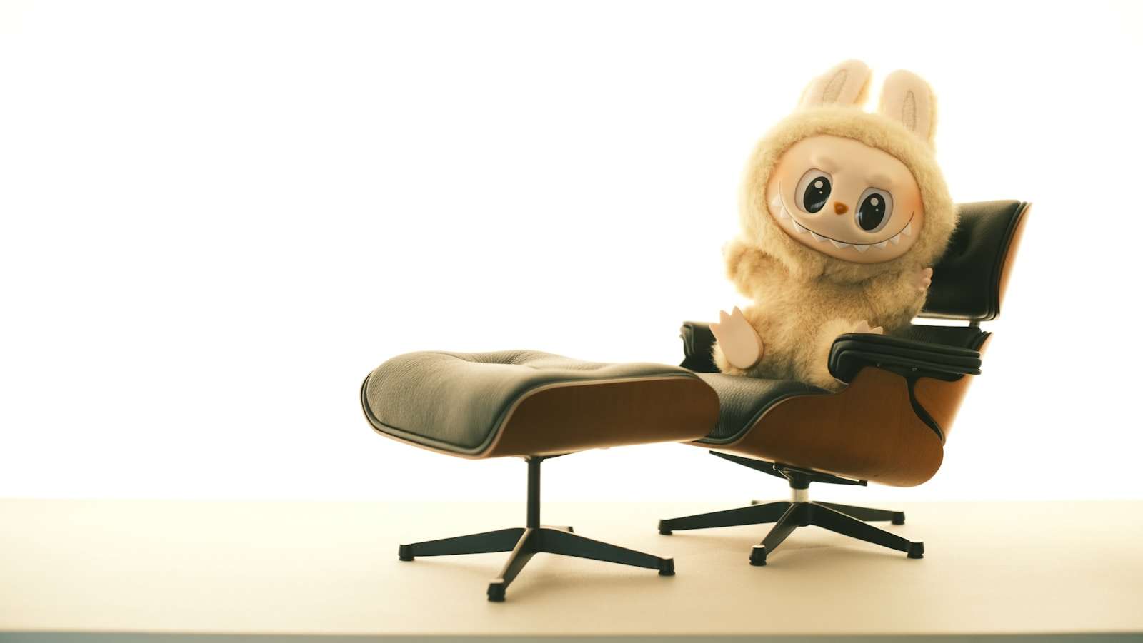 A cute stuffed animal sits on a comfortable chair. Labubu